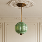 Vintage green sculpted glass semi-flush ceiling light with antique brass hardware in a classic period-style room.