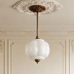 Vintage semi-flush ceiling light with a white sculpted glass globe shade and antique brass hardware in a classic interior.