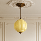 Vintage yellow sculpted glass semi-flush ceiling light with antique brass hardware in a period-style room.