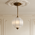 Vintage semi-flush ceiling light with a frosted, sculpted glass globe and ornate antique brass hardware.