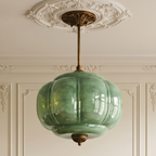 Vintage green sculpted glass semi-flush ceiling light with antique brass hardware in a classic interior.
