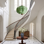 Large green sculpted glass semi-flush ceiling light hanging in a bright, elegant foyer with a curved staircase.