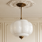 Vintage semi-flush ceiling light with a white sculpted glass shade and antique brass hardware on a decorative ceiling rose.