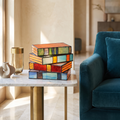 Vintage stained glass table lamp shaped like a stack of colorful books glowing on a marble side table.