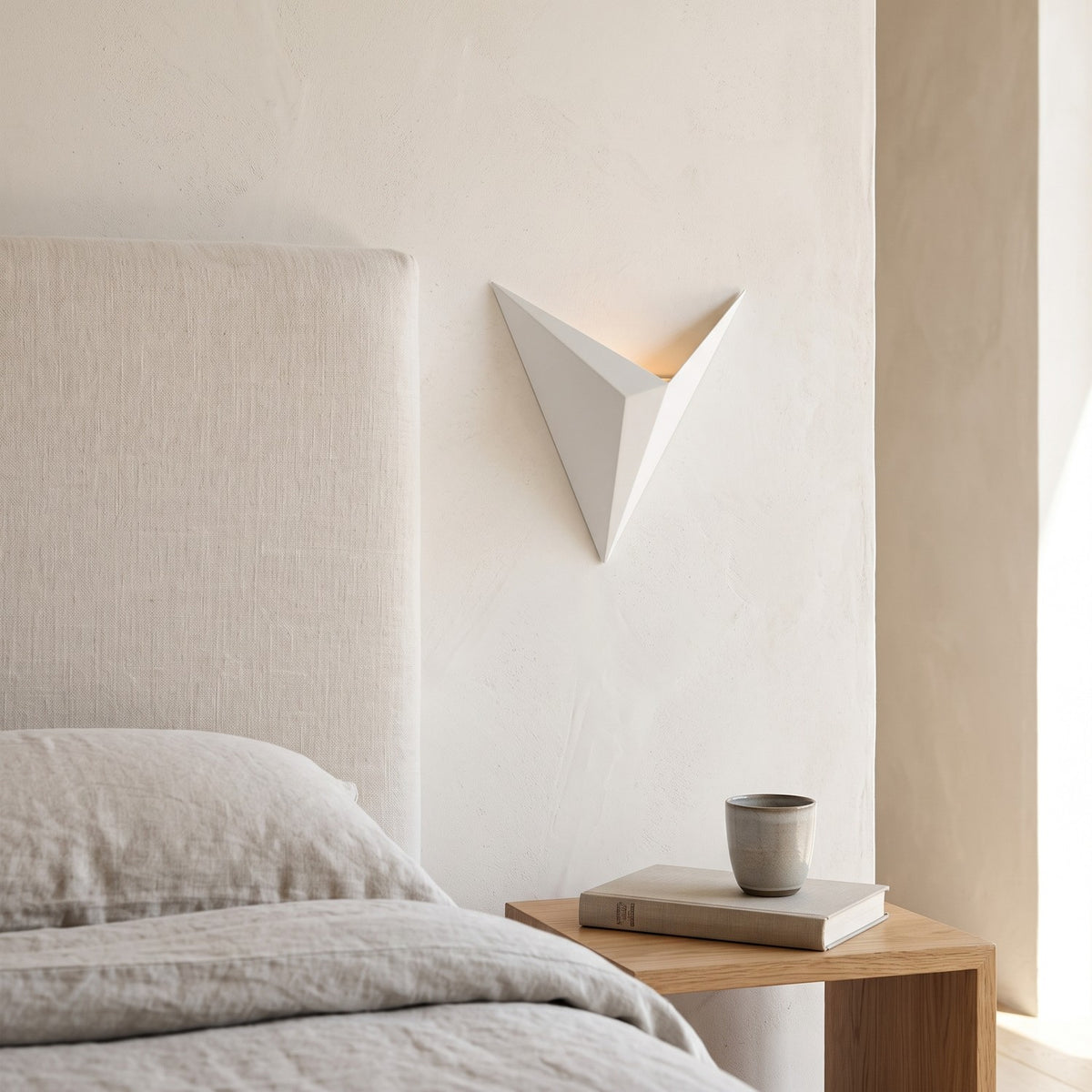 Triangle LED Wall Light in white beside a linen headboard in a serene bedroom