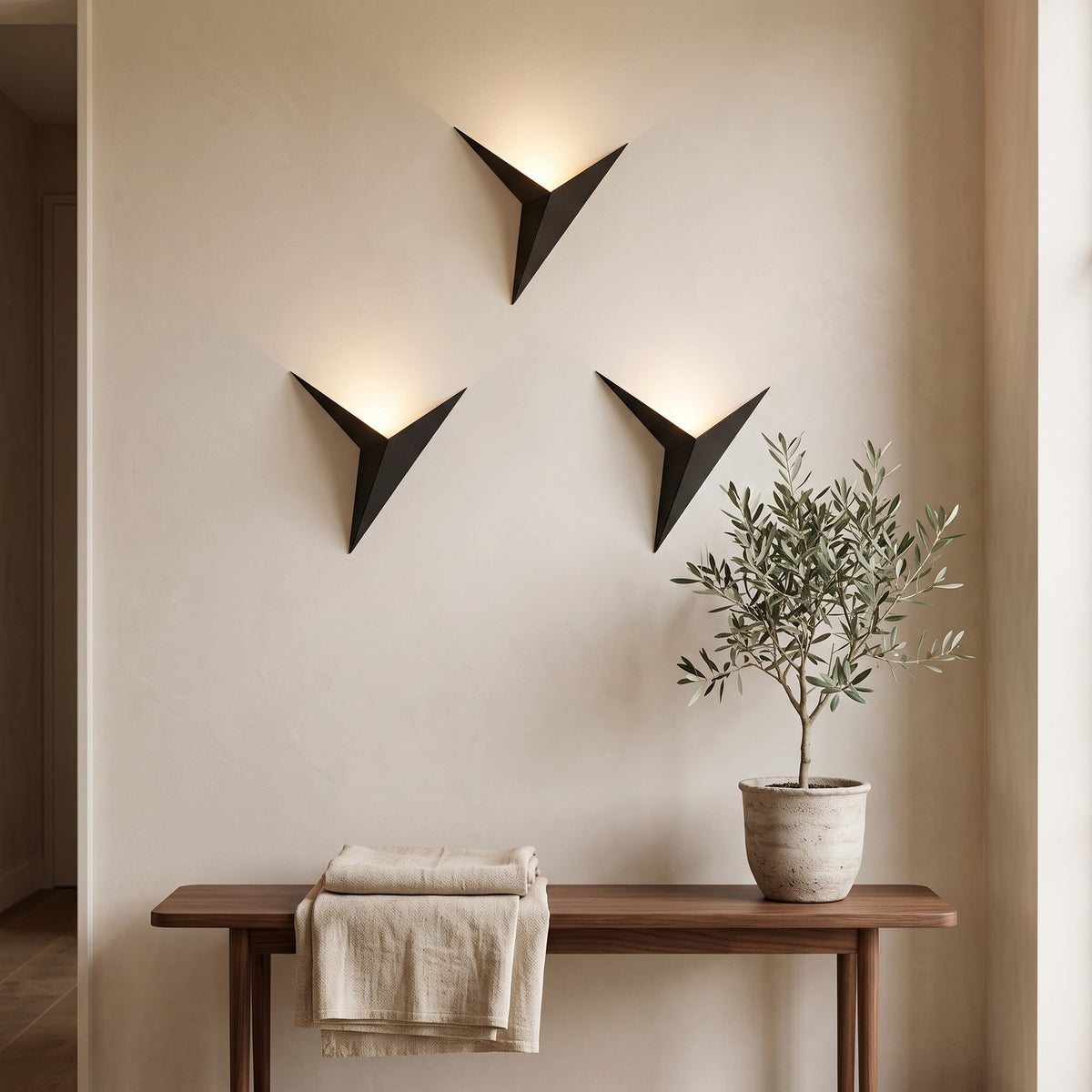 Three black Triangle LED Wall Lights glowing above a walnut bench in an entrance hall