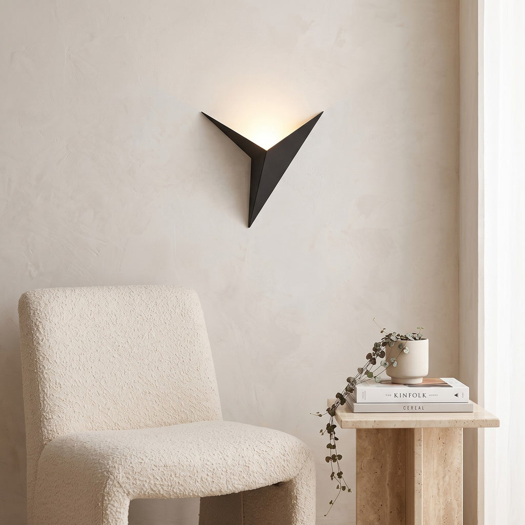 Triangle LED Wall Light in black above a boucle armchair in a reading corner