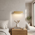Up Down LED Wall Light – Gold in a serene bedroom beside an upholstered headboard and oak nightstand