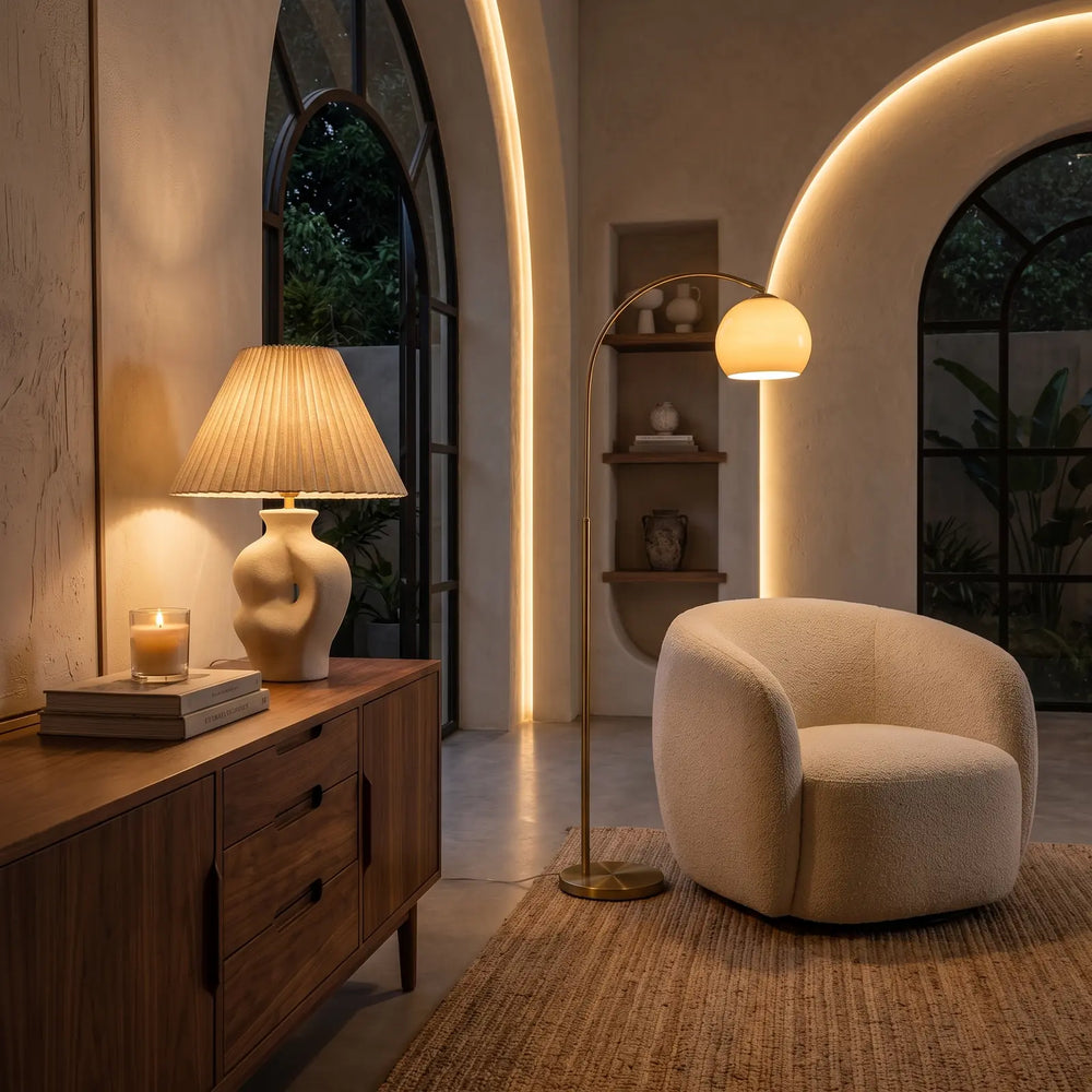 Ceramic table lamp and arc floor lamp beside a boucle armchair